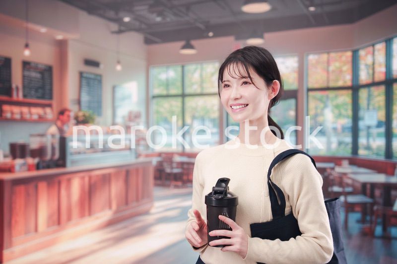 マイカップを持ってカフェに入る若い女性