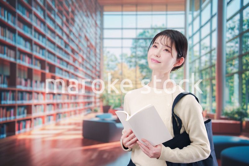 明るい図書館で本を読む若い女性