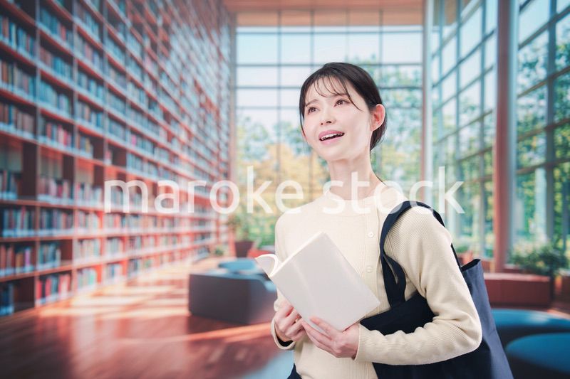 明るい図書館で本を読む若い女性