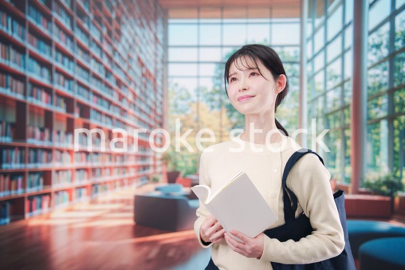 明るい図書館で本を読む若い女性