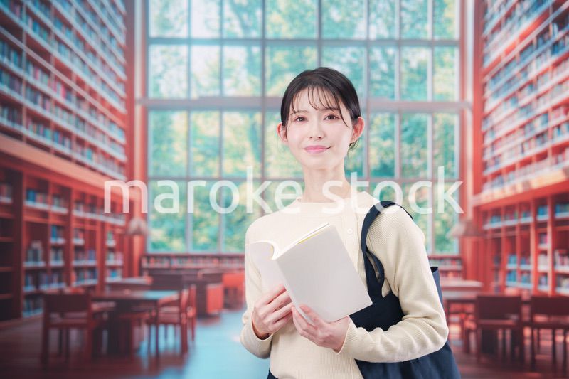 明るい図書館で本を読む若い女性