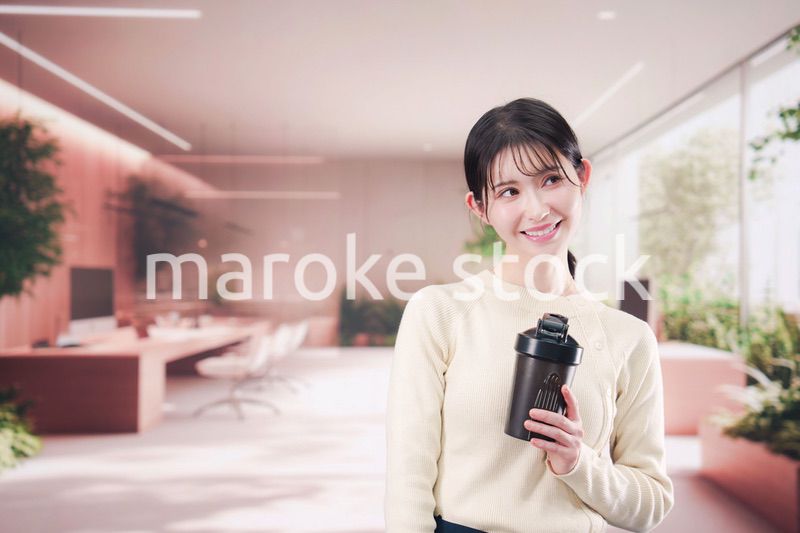オフィスでマイボトルを持ち歩く若い女性