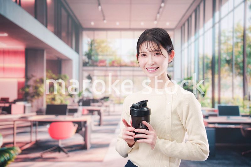 オフィスでマイボトルを持ち歩く若い女性