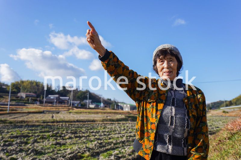 田舎で上を指差す高齢の女性