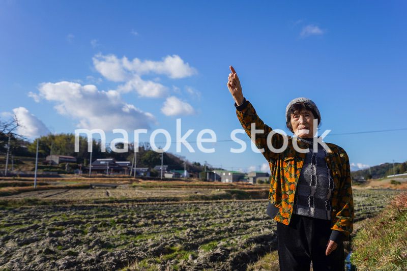 田舎で上を指差す高齢の女性
