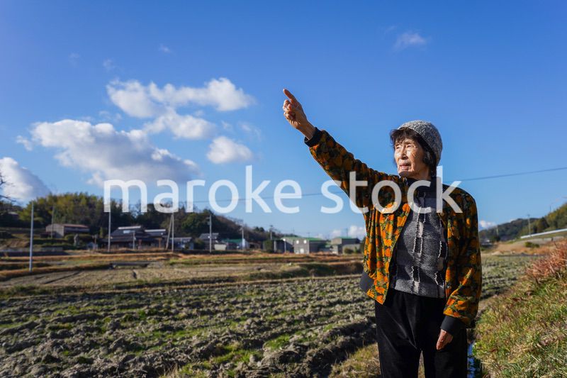 田舎で上を指差す高齢の女性