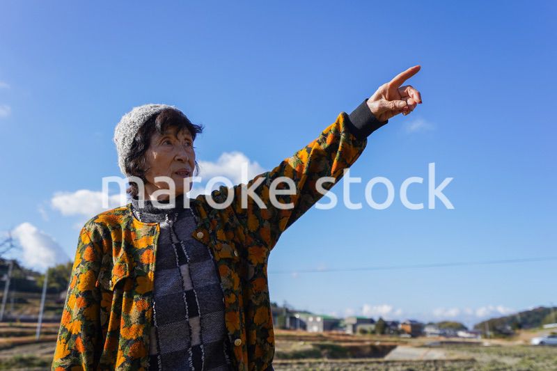 田舎で上を指差す高齢の女性