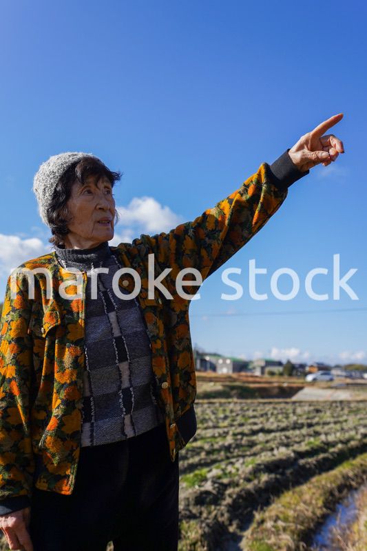 田舎で上を指差す高齢の女性