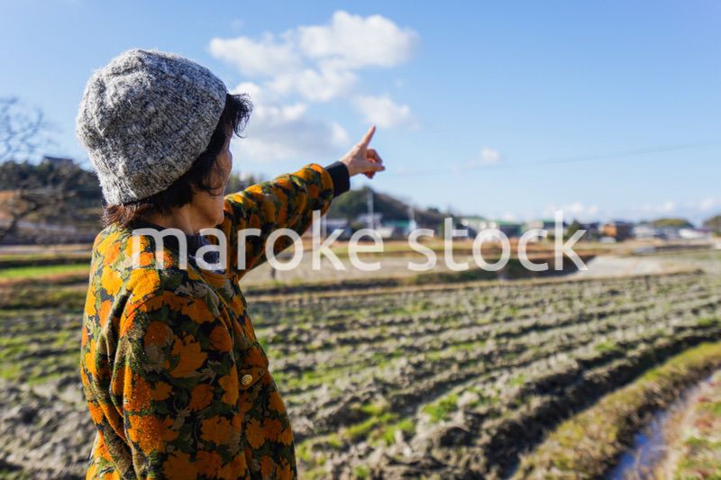 田舎で上を指差す高齢の女性