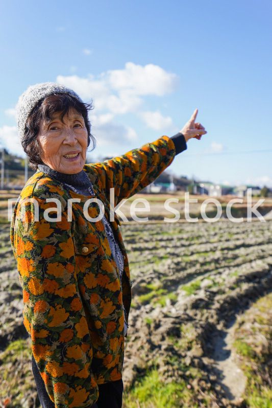 田舎で上を指差す高齢の女性