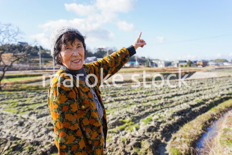 田舎で上を指差す高齢の女性