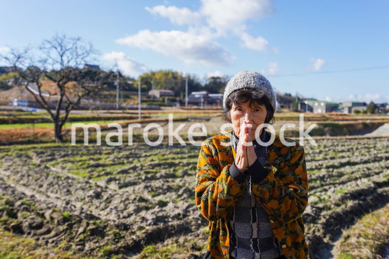 田舎でお祈りをする高齢の女性