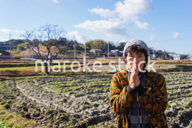 田舎でお祈りをする高齢の女性