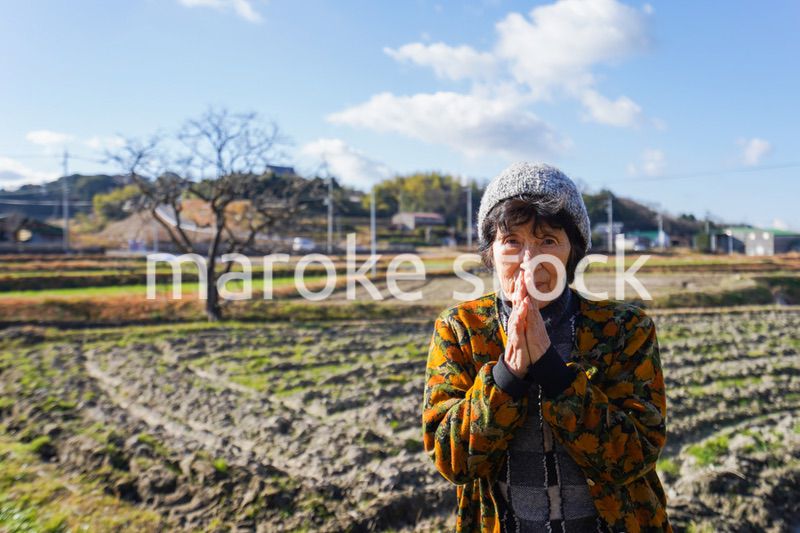 田舎でお祈りをする高齢の女性