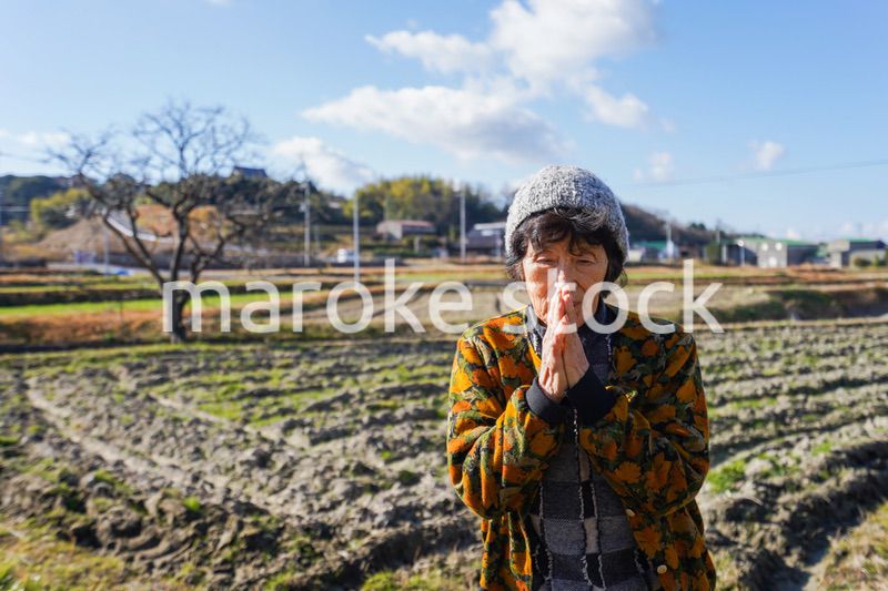 田舎でお祈りをする高齢の女性