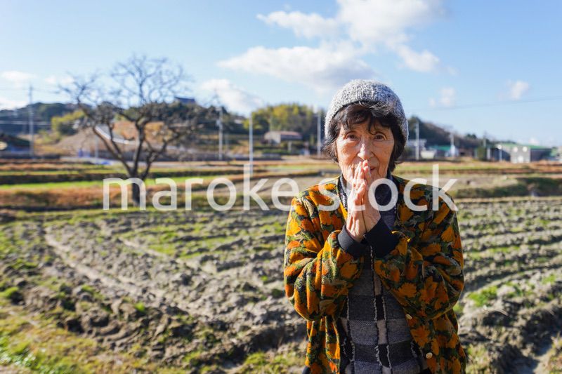 田舎でお祈りをする高齢の女性