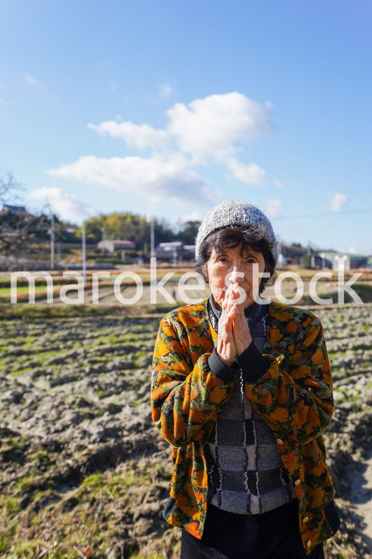 田舎でお祈りをする高齢の女性