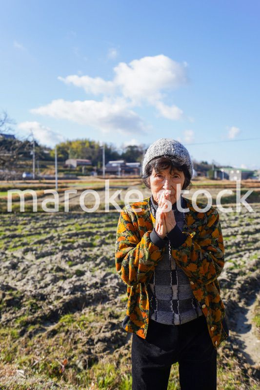 田舎でお祈りをする高齢の女性