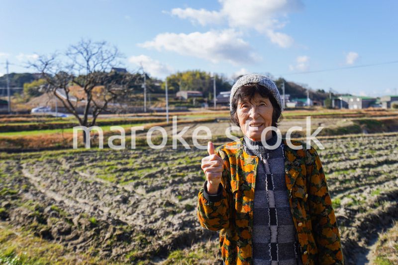 田舎でグッドサインをする高齢の女性