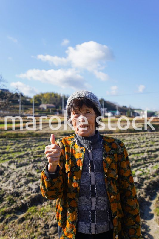 田舎でグッドサインをする高齢の女性