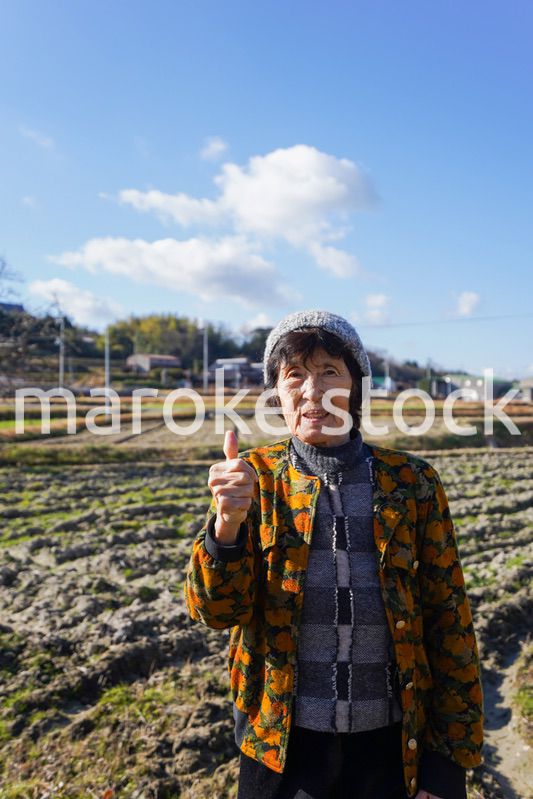 田舎でグッドサインをする高齢の女性