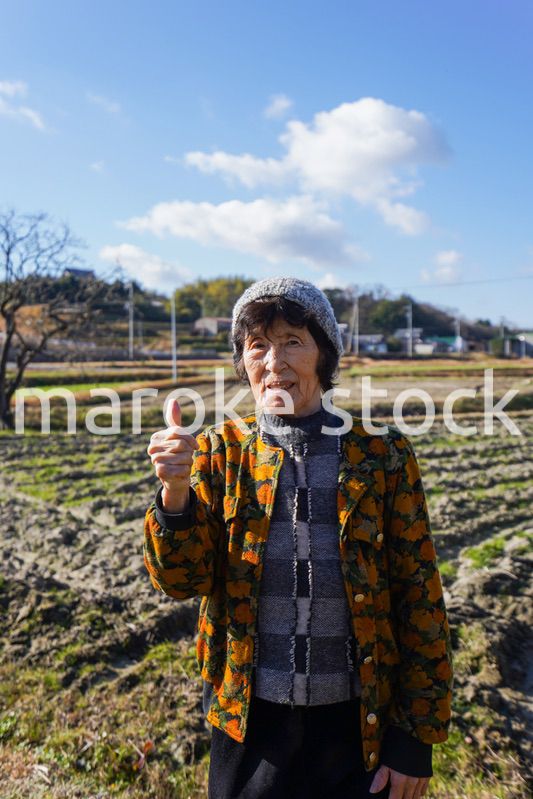 田舎でグッドサインをする高齢の女性