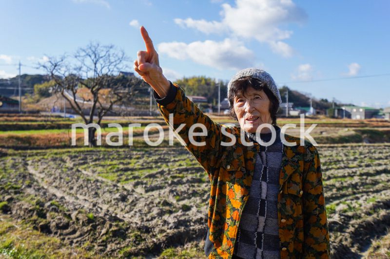 田舎で上を指差す高齢の女性