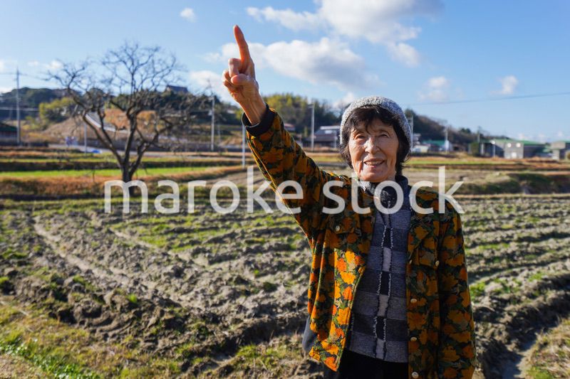 田舎で上を指差す高齢の女性