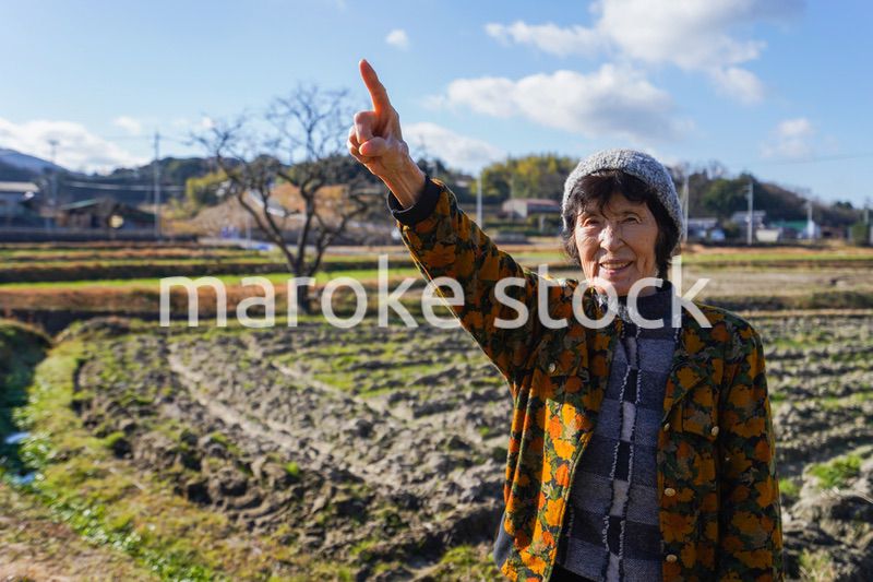 田舎で上を指差す高齢の女性
