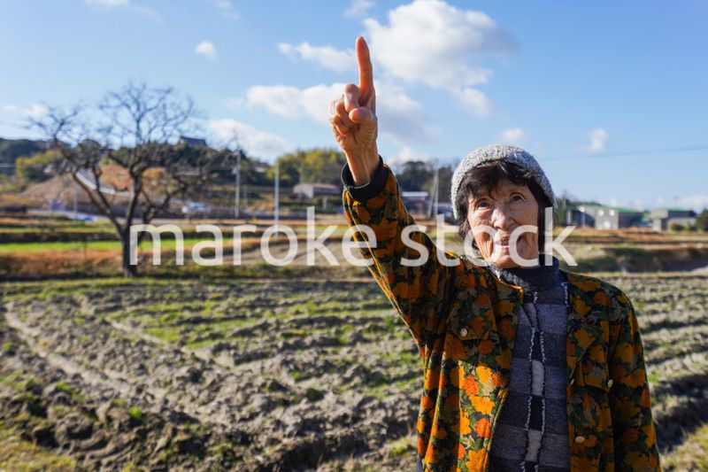 田舎で上を指差す高齢の女性