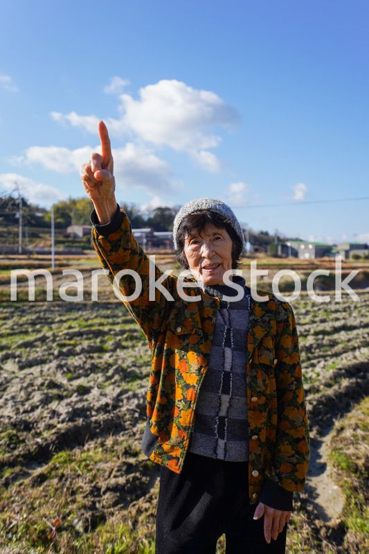 田舎で上を指差す高齢の女性