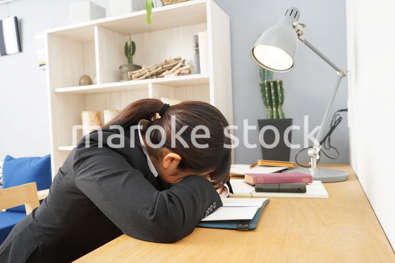 スーツを着て机で寝る女性