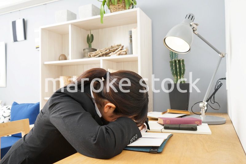 スーツを着て机で寝る女性