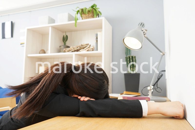 スーツを着て机で寝る女性