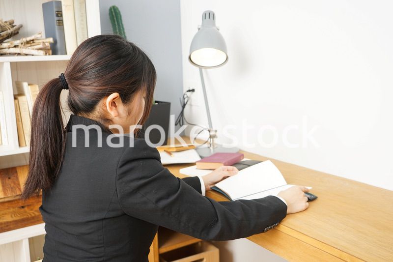 スーツを着て机で寝る女性