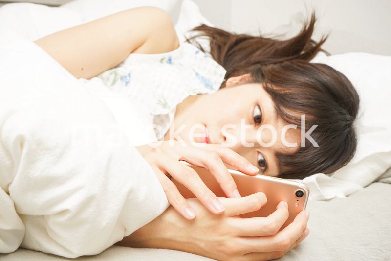 寝る前に携帯を使う若い女性