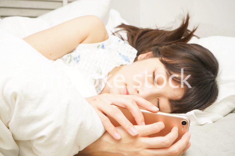 寝る前に携帯を使う若い女性