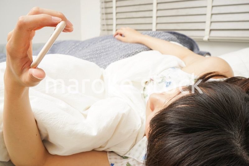 寝る前に携帯を使う若い女性