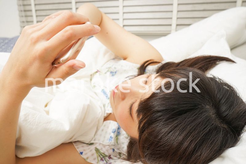 寝る前に携帯を使う若い女性