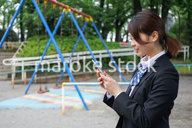 笑顔でスマホを使う制服姿の学生