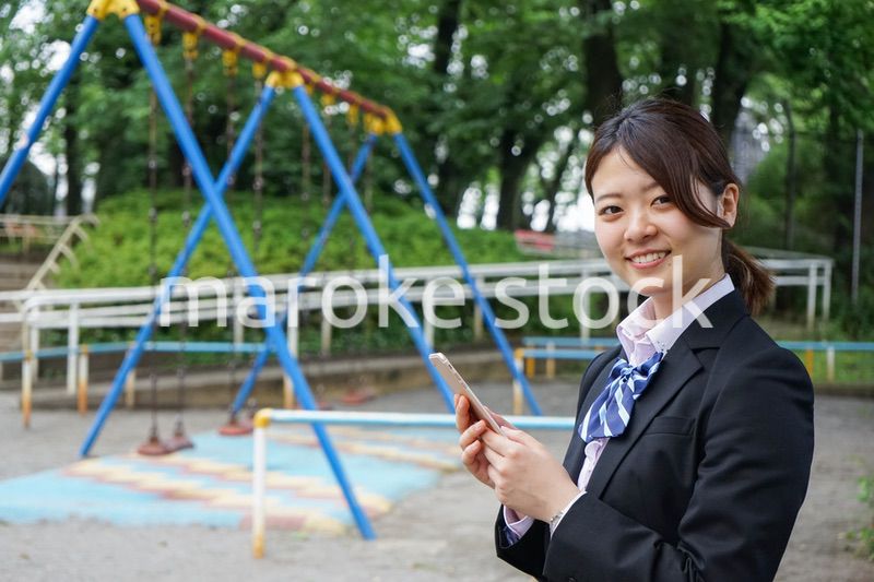 笑顔でスマホを使う制服姿の学生