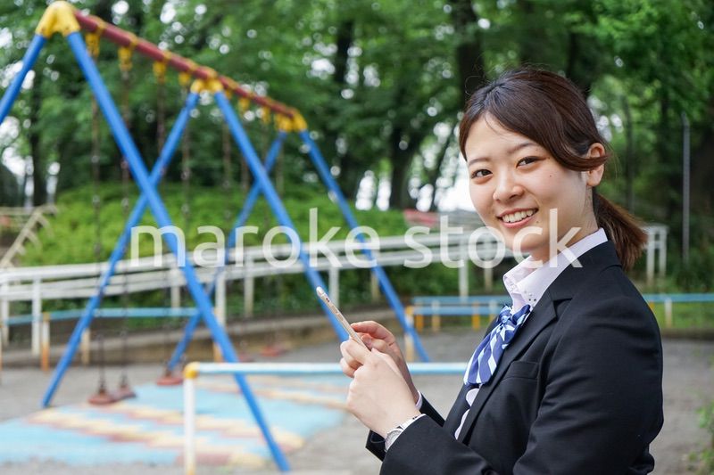 笑顔でスマホを使う制服姿の学生