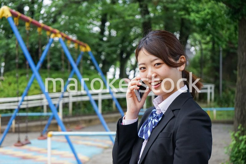 笑顔でスマホを使う制服姿の学生