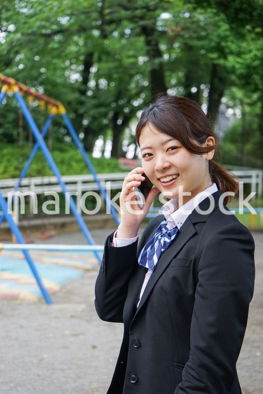 笑顔でスマホを使う制服姿の学生