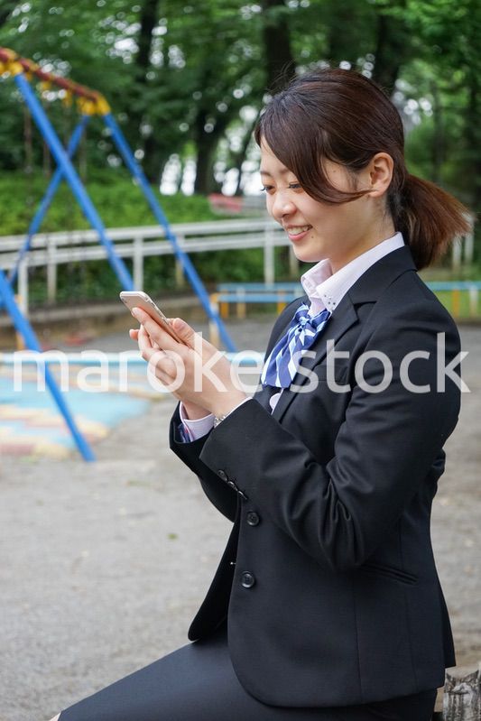 笑顔でスマホを使う制服姿の学生