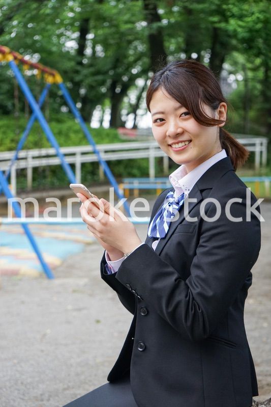 笑顔でスマホを使う制服姿の学生