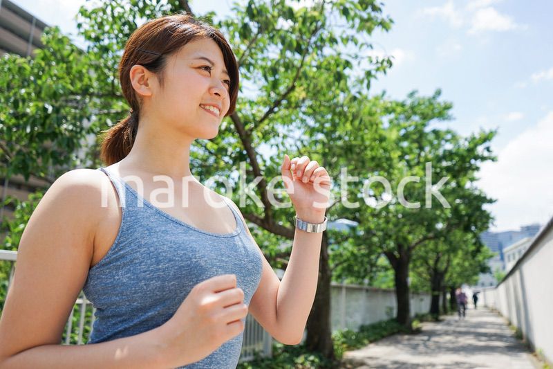 都会をランニングする若い女性