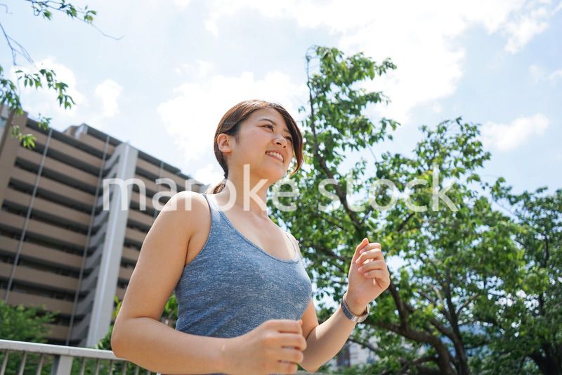 都会をランニングする若い女性