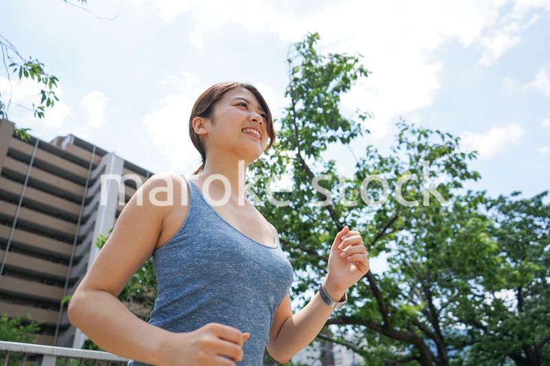 都会をランニングする若い女性