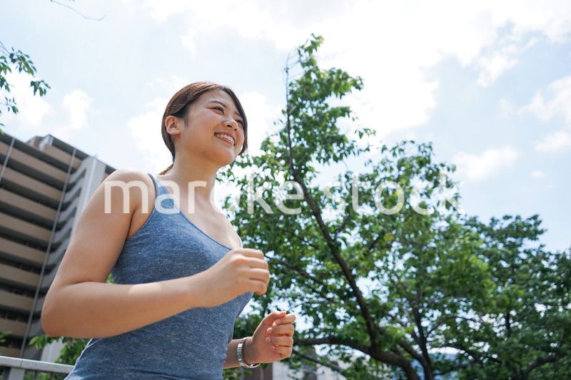 都会をランニングする若い女性